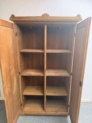 fig 1. An Arts and Crafts waxed pine two-door wardrobe featuring shallow carved floral door panels and a carved top cresting rail.