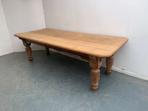 A large Victorian golden oak dining table featuring a thick rectangular top with rounded corners and four turned wooden legs.