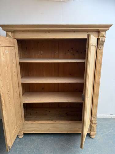 fig 2. A double-door Victorian stripped pine wardrobe featuring carved corbels, moulded door panels, and turned bun feet.