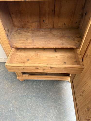 fig 1. A tall Victorian stripped pine cupboard with a single panelled door, carved accents near the top corners, and turned bun feet.