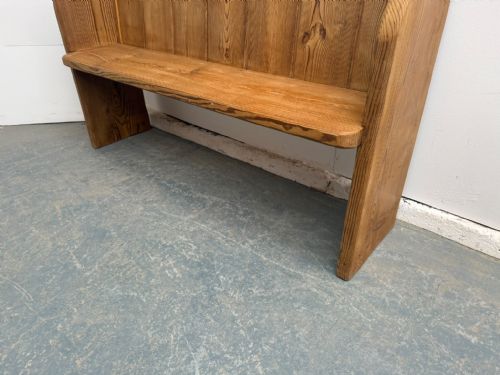 fig 1. A two-seater waxed pine church pew featuring a vertical panelled backrest and curved solid side supports.