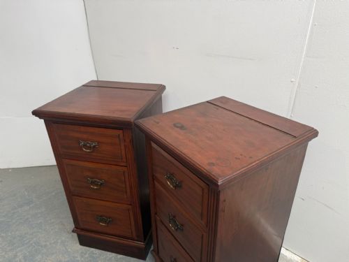 fig 1. A pair of narrow mahogany bedside chests featuring three drawers each with brass handles on a plinth base.
