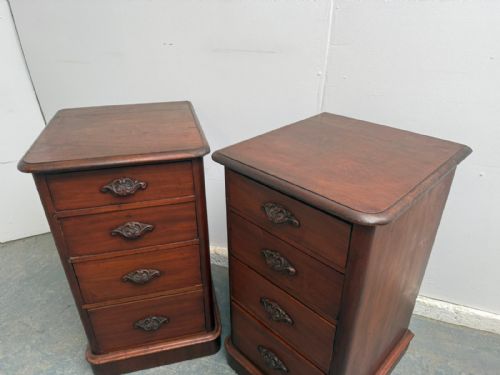 fig 1. A pair of narrow dark mahogany bedside cabinets featuring four stacked drawers with ornate metal handles on a plinth base.