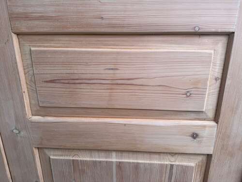 fig 2. A single-door antique stripped pine wardrobe featuring recessed panel detailing, a flared top cornice, an iron keyhole, and flattened bun feet.