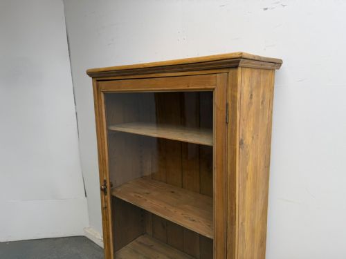 fig 1. A Victorian waxed pine display cabinet featuring a single glazed door and interior adjustable wooden shelves.