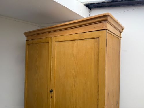 fig 1. A large two-door Victorian waxed pine cupboard featuring recessed panel doors, two bottom drawers, turned wooden knobs, and a stepped top moulding.