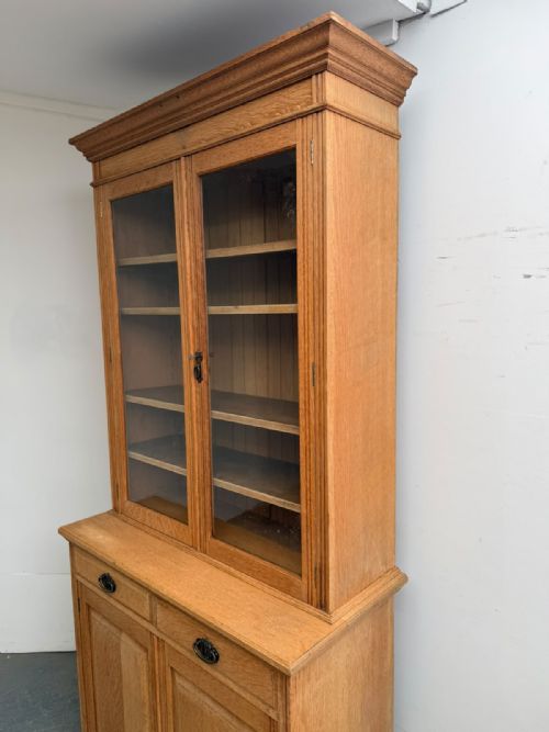 fig 1. A two-piece Arts and Crafts oak cabinet with upper glazed double doors and lower panelled cupboard doors with two drawers.