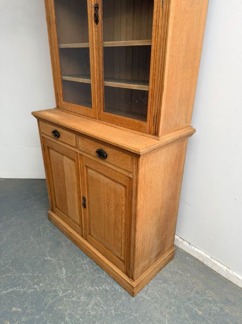 fig 2. A two-piece Arts and Crafts oak cabinet with upper glazed double doors and lower panelled cupboard doors with two drawers.
