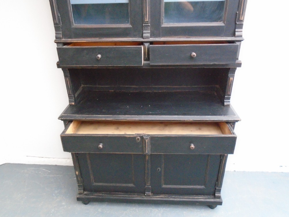 A two-piece Victorian kitchen dresser in distressed black painted pine, featuring a glazed upper cabinet above drawers and a lower two-door cupboard. View VIII