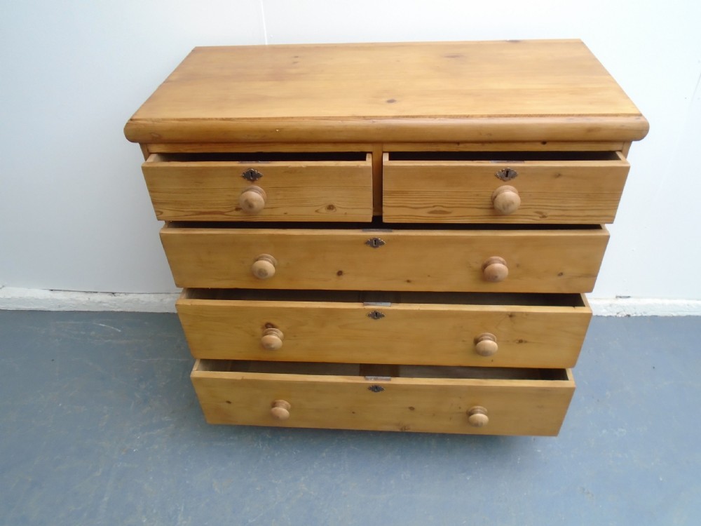 A Victorian waxed pine chest featuring two short over three long graduating drawers with turned wooden knobs. View IX