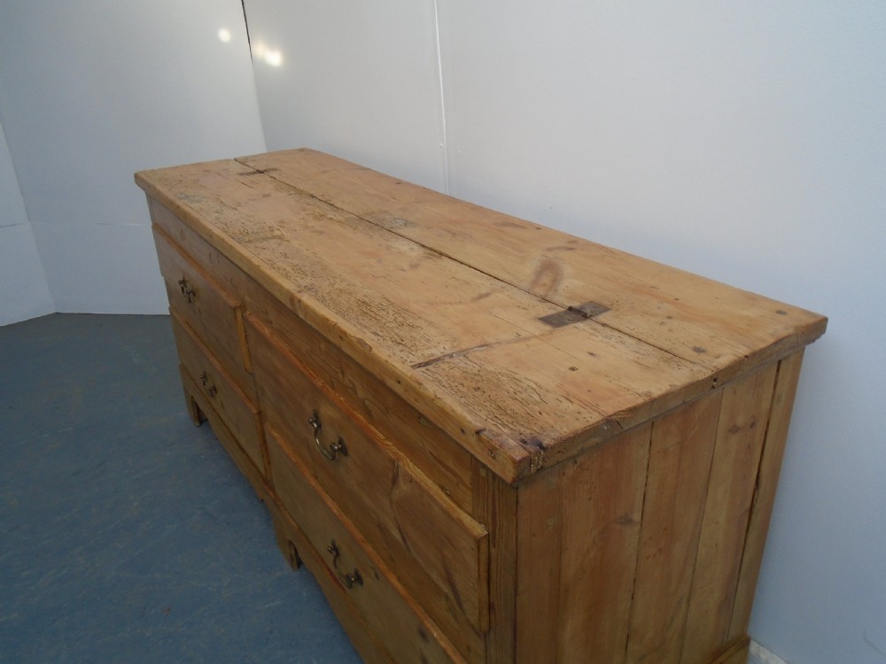 An extra wide Georgian waxed pine blanket box featuring a hinged top lid, brass swan-neck handles, faux drawer fronts, and a bracket base. View IV