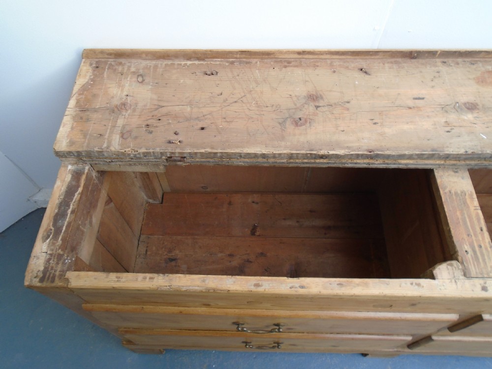An extra wide Georgian waxed pine blanket box featuring a hinged top lid, brass swan-neck handles, faux drawer fronts, and a bracket base. View VI