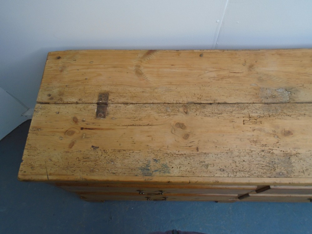 An extra wide Georgian waxed pine blanket box featuring a hinged top lid, brass swan-neck handles, faux drawer fronts, and a bracket base. View VII