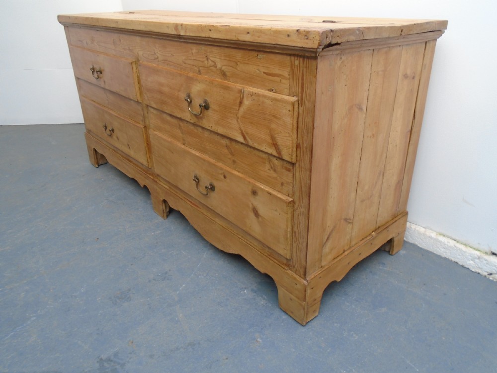 An extra wide Georgian waxed pine blanket box featuring a hinged top lid, brass swan-neck handles, faux drawer fronts, and a bracket base. View X