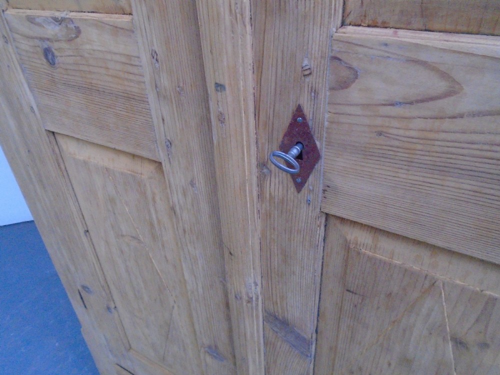 A tall Georgian natural pine storage cupboard featuring two fielded panel doors above a wide base drawer, set on turned bun feet. View VIII