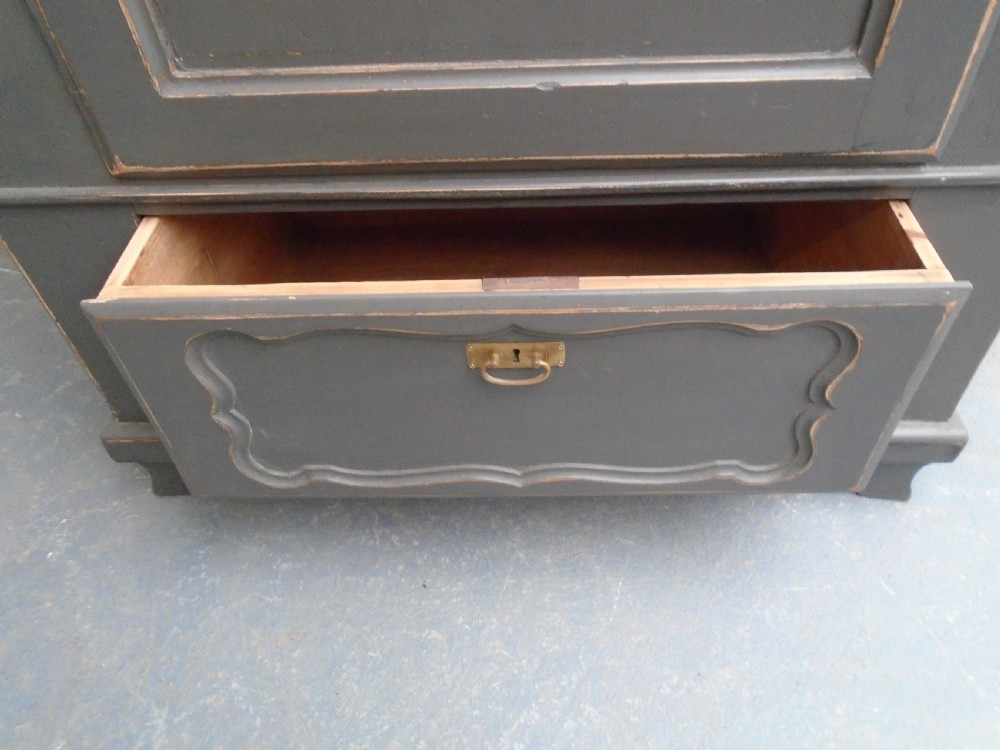A dark grey painted pine storage cupboard featuring a single panelled door with relief carving, a bottom drawer, and a stepped cornice. View VIII