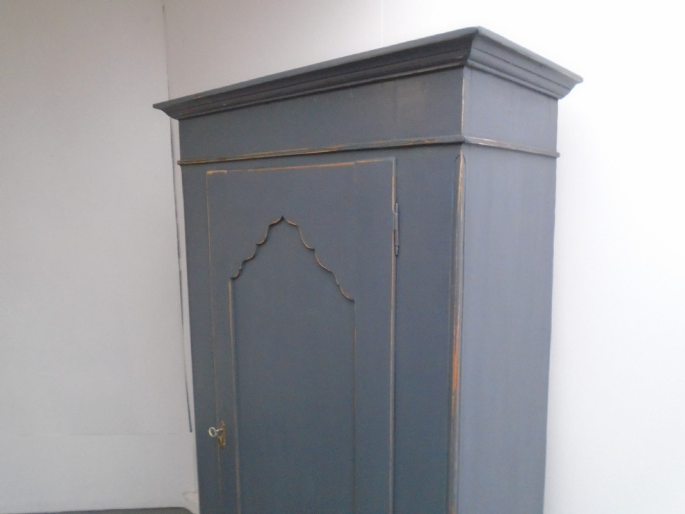 A tall Georgian painted pine cupboard in slate grey featuring a single panelled door with a scalloped insert and a lower drawer. View II