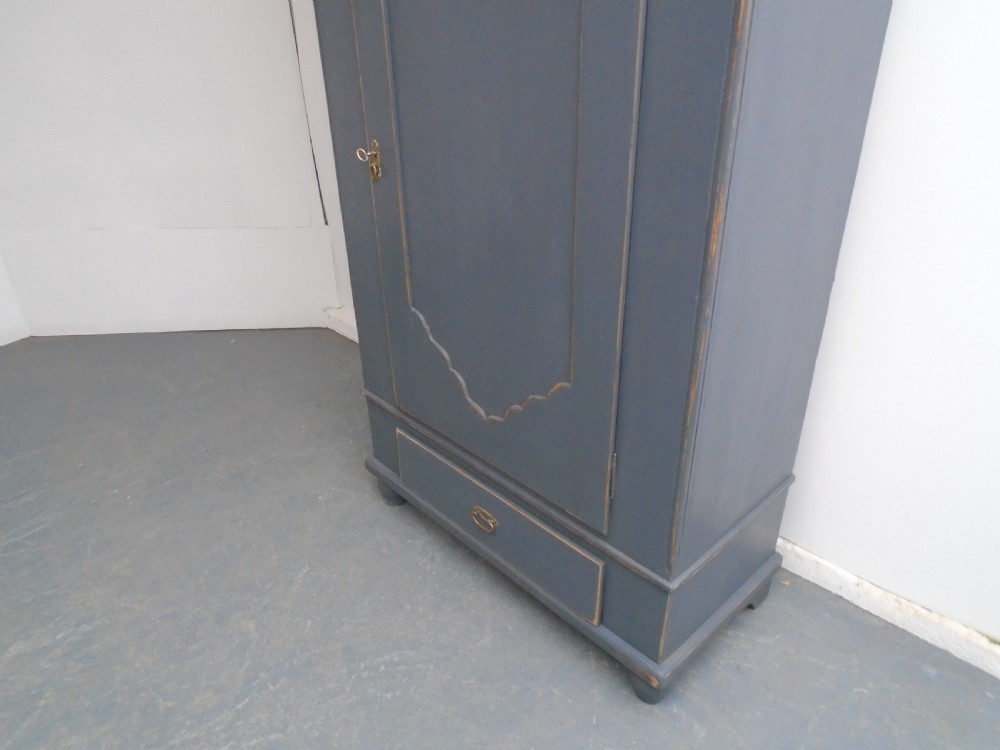 A tall Georgian painted pine cupboard in slate grey featuring a single panelled door with a scalloped insert and a lower drawer. View III