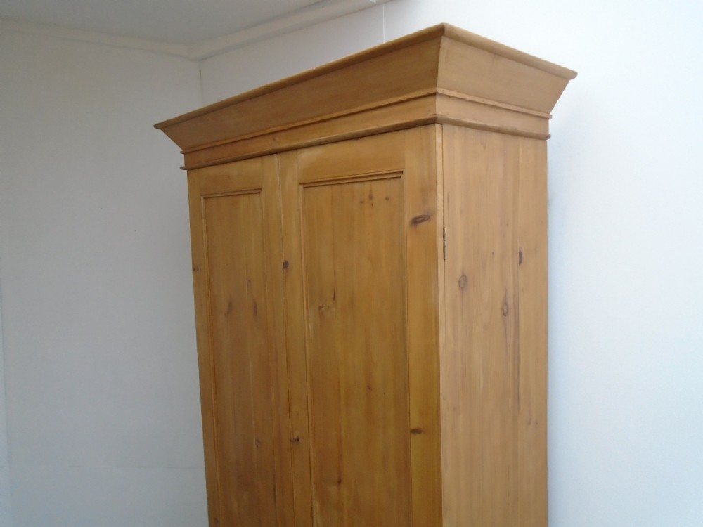 A tall Victorian waxed pine wardrobe featuring two panelled doors, a single bottom drawer with turned wooden knobs, and a moulded cornice. View II
