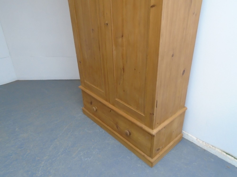 A tall Victorian waxed pine wardrobe featuring two panelled doors, a single bottom drawer with turned wooden knobs, and a moulded cornice. View IV