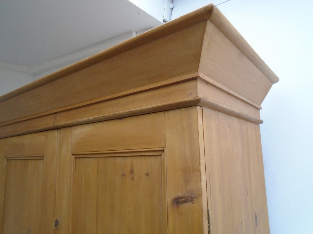 A tall Victorian waxed pine wardrobe featuring two panelled doors, a single bottom drawer with turned wooden knobs, and a moulded cornice. View VII