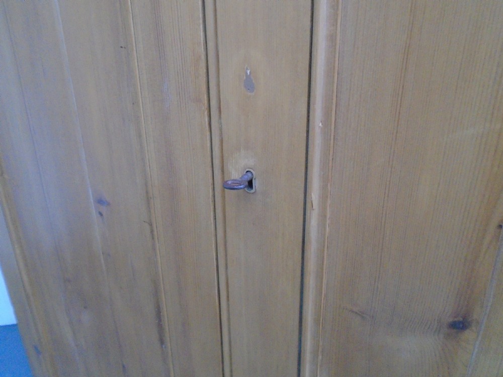 A tall Victorian waxed pine wardrobe featuring two panelled doors, a single bottom drawer with turned wooden knobs, and a moulded cornice. View VIII