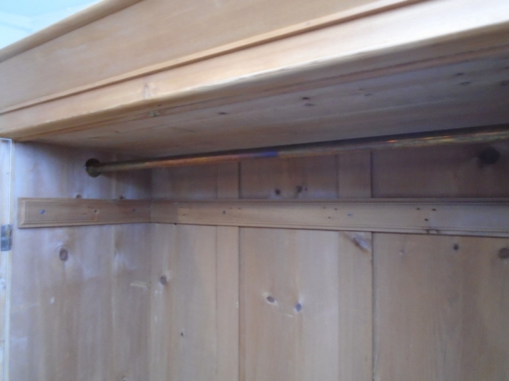 A tall Victorian waxed pine wardrobe featuring two panelled doors, a single bottom drawer with turned wooden knobs, and a moulded cornice. View XI