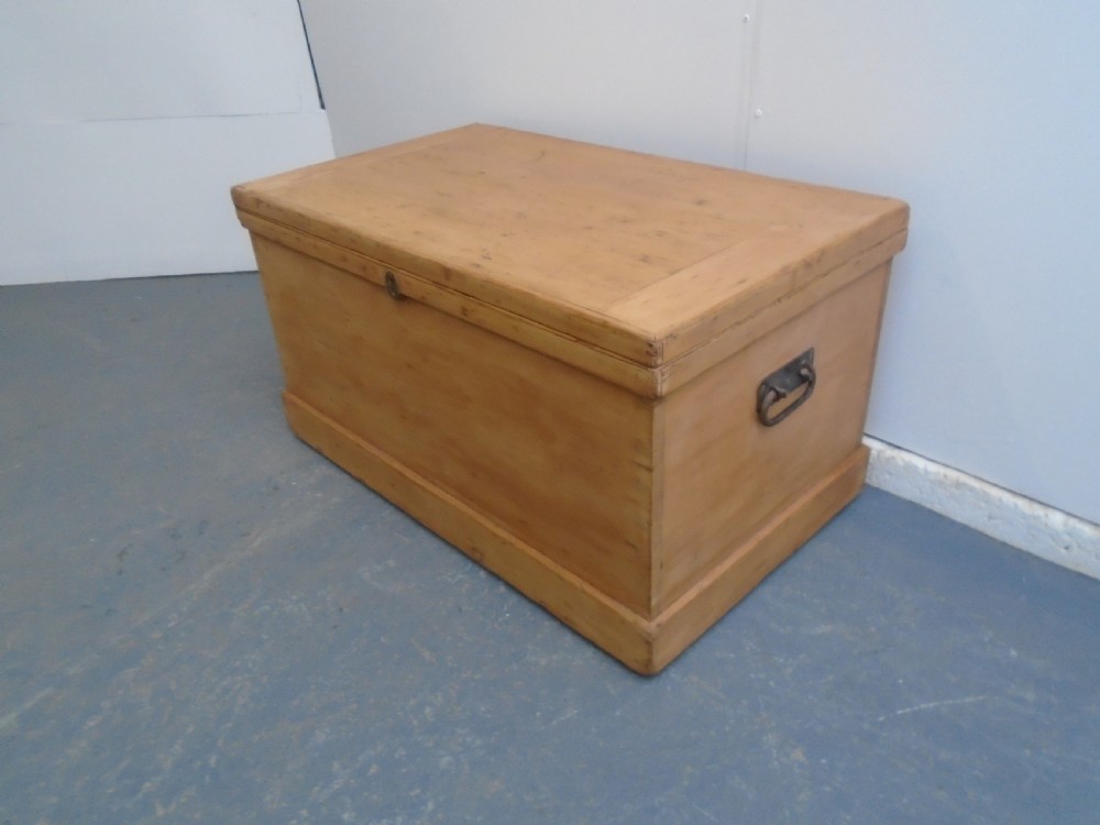 A rectangular Victorian waxed pine blanket box with side iron handles and a plinth base.