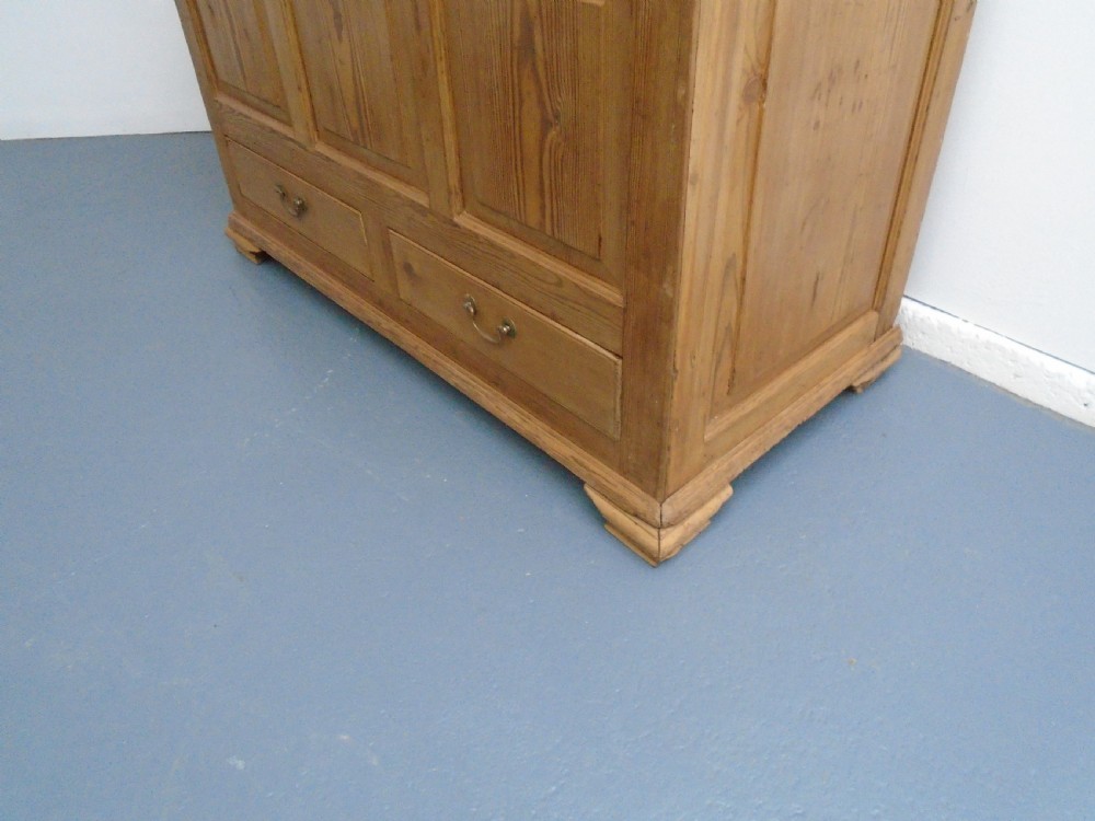 A waxed pine Georgian mule chest featuring a hinged top lid, three front panels, two lower drawers with brass handles, and a moulded plinth base. View III
