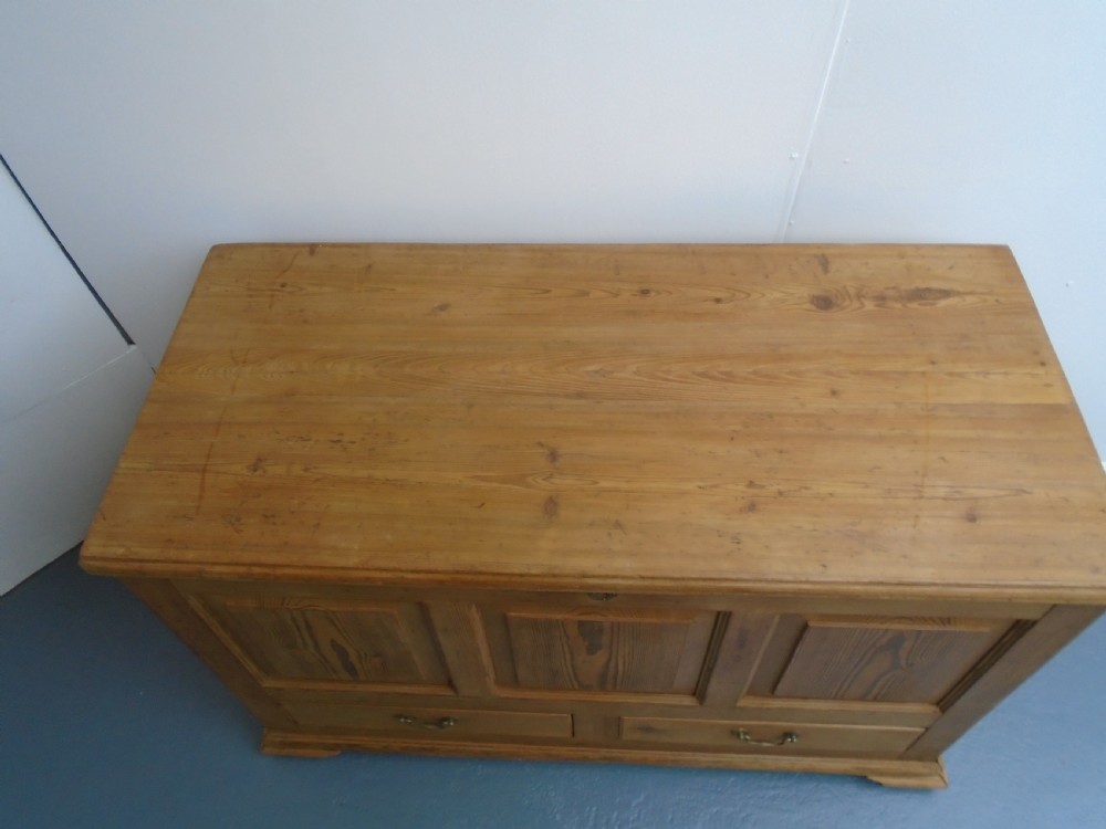 A waxed pine Georgian mule chest featuring a hinged top lid, three front panels, two lower drawers with brass handles, and a moulded plinth base. View VIII