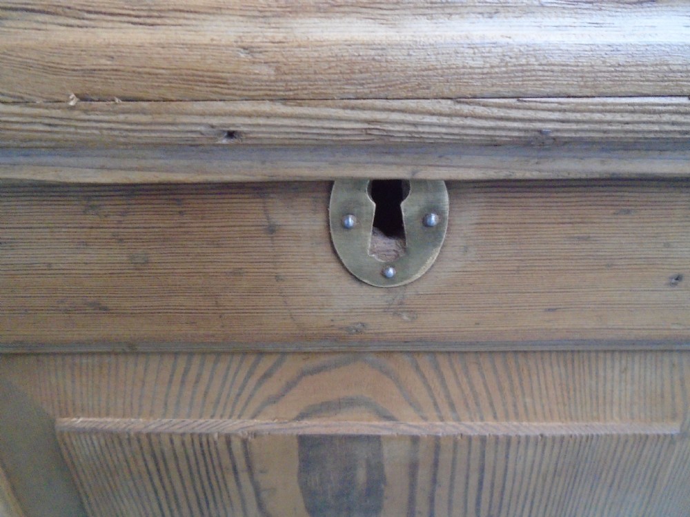 A waxed pine Georgian mule chest featuring a hinged top lid, three front panels, two lower drawers with brass handles, and a moulded plinth base. View IX