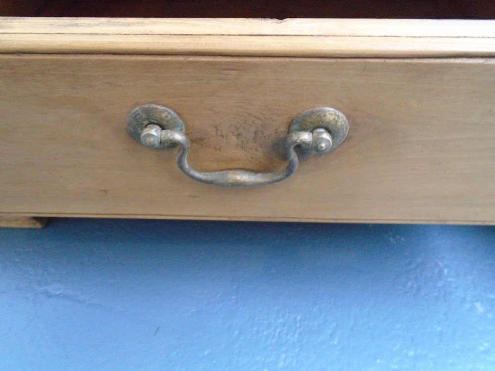 A waxed pine Georgian mule chest featuring a hinged top lid, three front panels, two lower drawers with brass handles, and a moulded plinth base. View XI