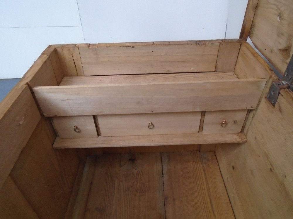 A waxed pine Georgian mule chest featuring a hinged top lid, three front panels, two lower drawers with brass handles, and a moulded plinth base. View XIII