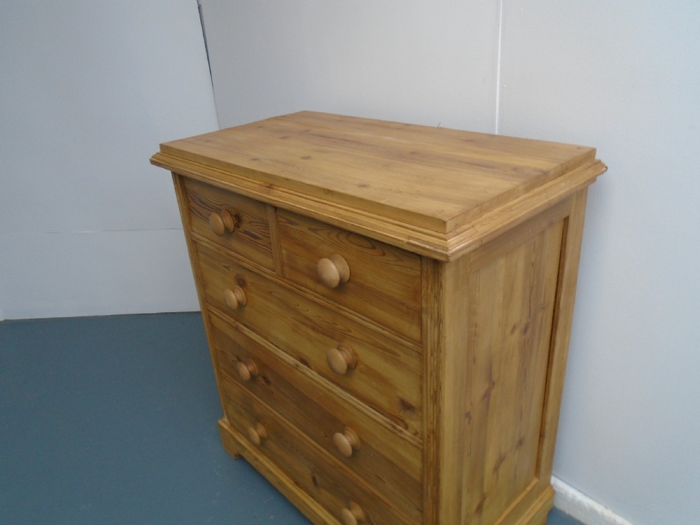 A waxed Victorian pine chest of drawers featuring a two-short-over-three-long drawer layout, panelled sides, and turned wooden knobs. View II