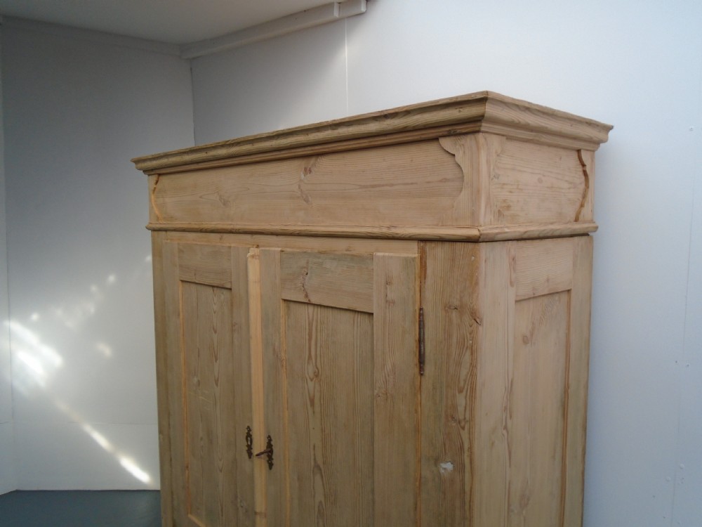 An unpainted Georgian pine two-door wardrobe featuring recessed panel doors, side panel construction, and a prominent moulded upper cornice. View II