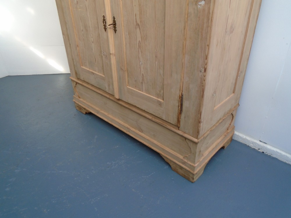 An unpainted Georgian pine two-door wardrobe featuring recessed panel doors, side panel construction, and a prominent moulded upper cornice. View III