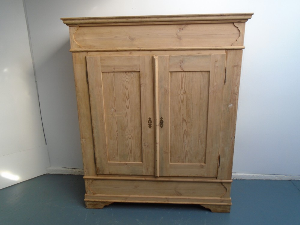 An unpainted Georgian pine two-door wardrobe featuring recessed panel doors, side panel construction, and a prominent moulded upper cornice. View IV