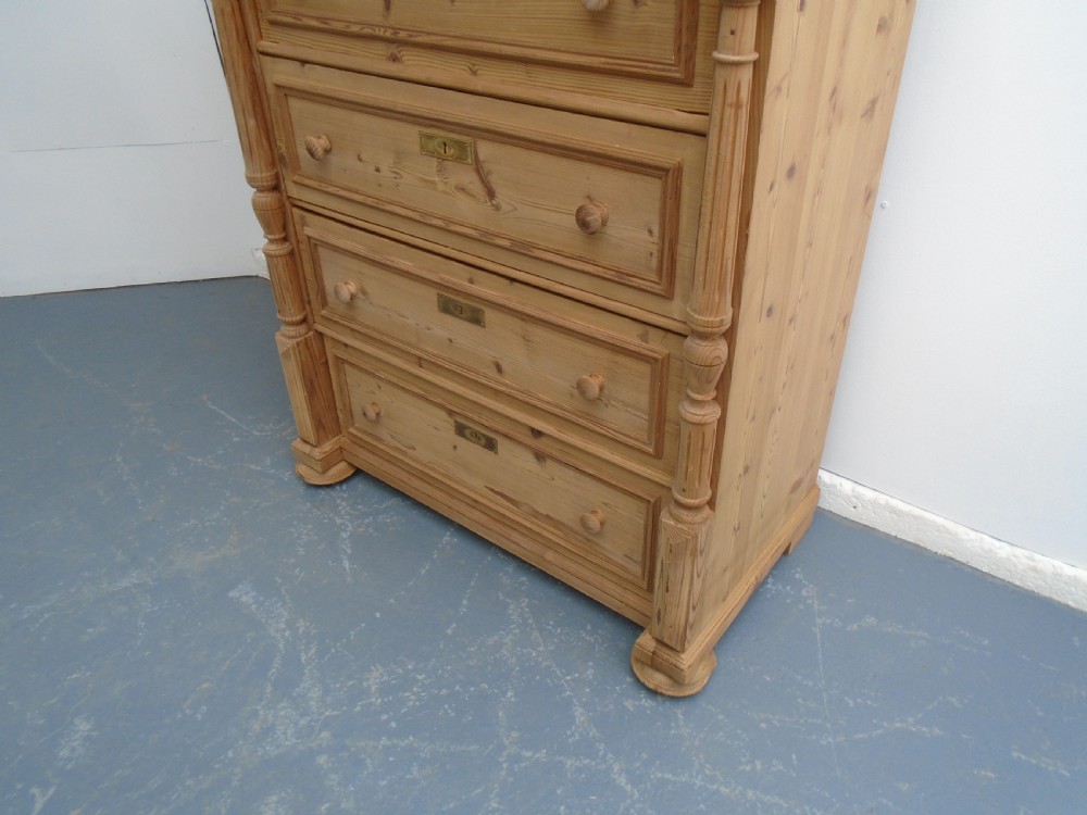 A tall Victorian stripped pine chest featuring five drawers, turned side columns, wooden knobs, and brass escutcheons. View III
