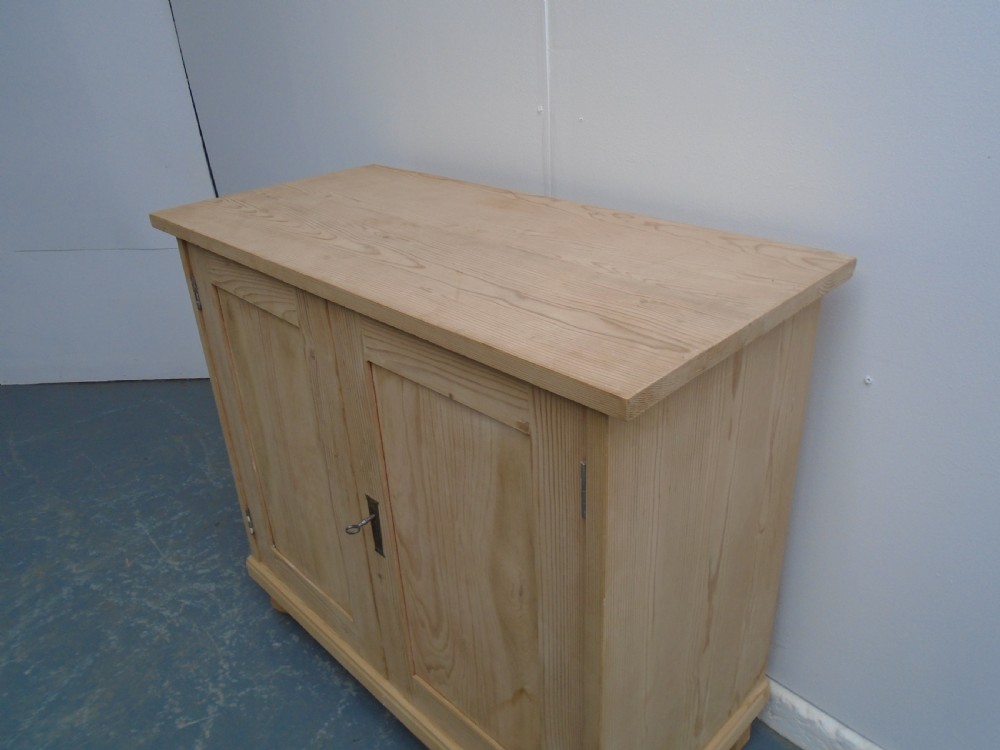 A low rectangular Victorian pine cupboard featuring two panelled doors, a central metal keyhole escutcheon, and turned bun feet. View II