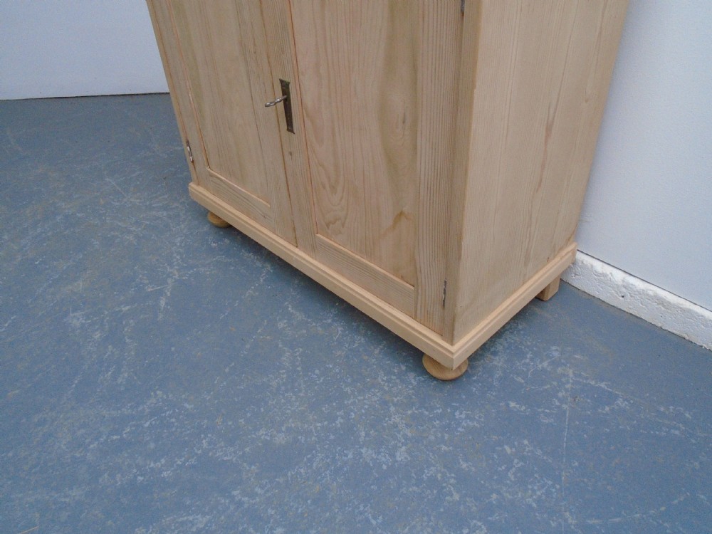 A low rectangular Victorian pine cupboard featuring two panelled doors, a central metal keyhole escutcheon, and turned bun feet. View III