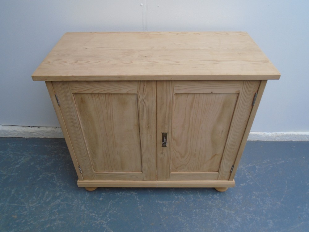 A low rectangular Victorian pine cupboard featuring two panelled doors, a central metal keyhole escutcheon, and turned bun feet. View IV
