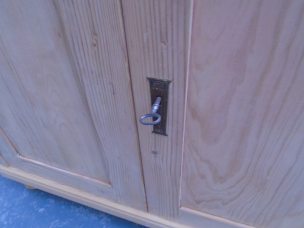 A low rectangular Victorian pine cupboard featuring two panelled doors, a central metal keyhole escutcheon, and turned bun feet. View VII