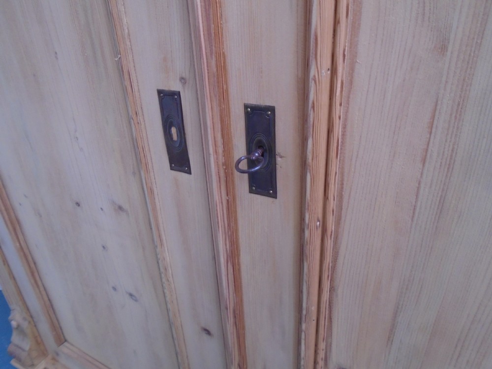 An unpainted Victorian pine double knockdown wardrobe featuring fluted side pilasters, panelled doors, a deep moulded cornice, and base drawers. View IX