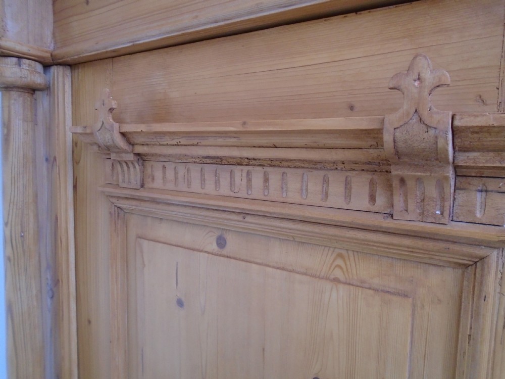 A large Victorian waxed pine double-door wardrobe featuring turned side columns, decorative pediments above the panelled doors, and a molded cornice. View VII