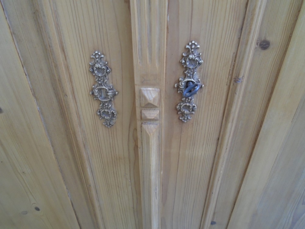 A large Victorian waxed pine double-door wardrobe featuring turned side columns, decorative pediments above the panelled doors, and a molded cornice. View IX