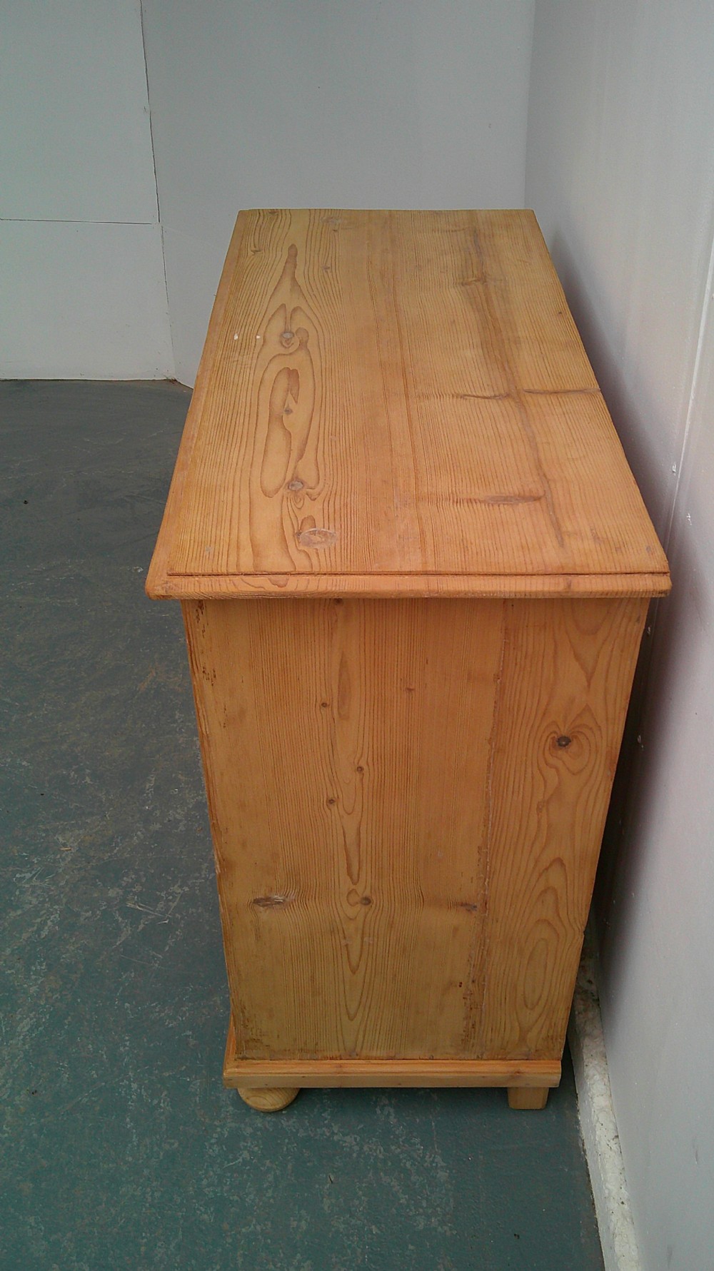 A Victorian pine dresser base featuring two drawers above a two-door cupboard with turned wooden knobs and bun feet. View V