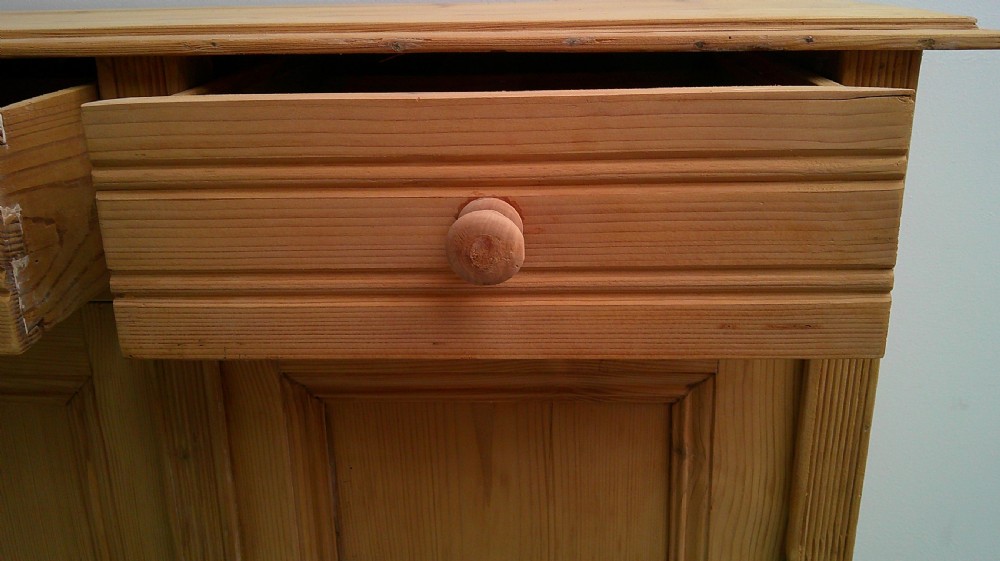 A Victorian pine dresser base featuring two drawers above a two-door cupboard with turned wooden knobs and bun feet. View VII