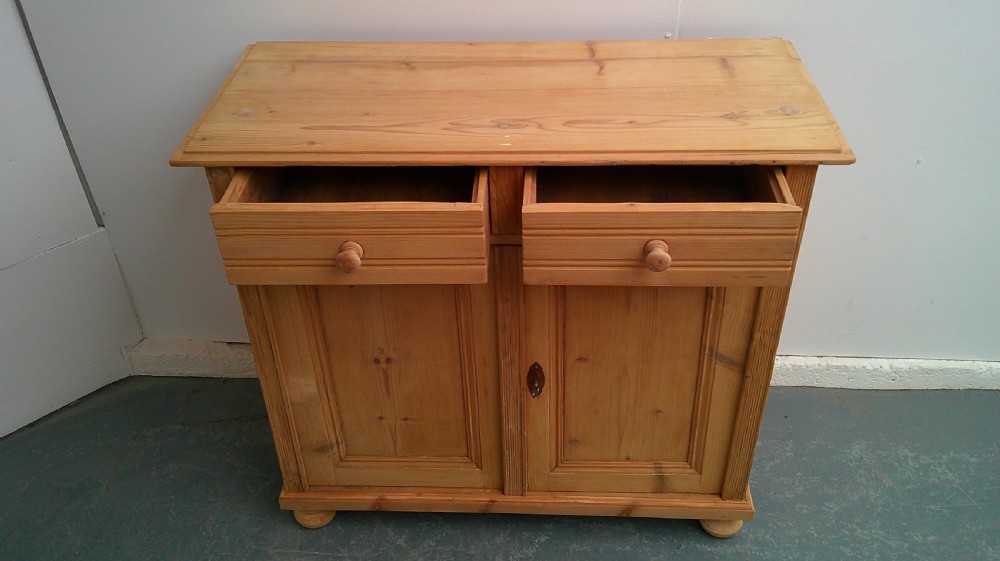 A Victorian pine dresser base featuring two drawers above a two-door cupboard with turned wooden knobs and bun feet. View VIII
