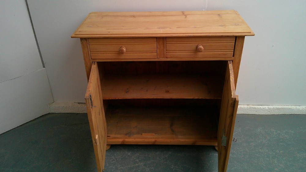 A Victorian pine dresser base featuring two drawers above a two-door cupboard with turned wooden knobs and bun feet. View IX