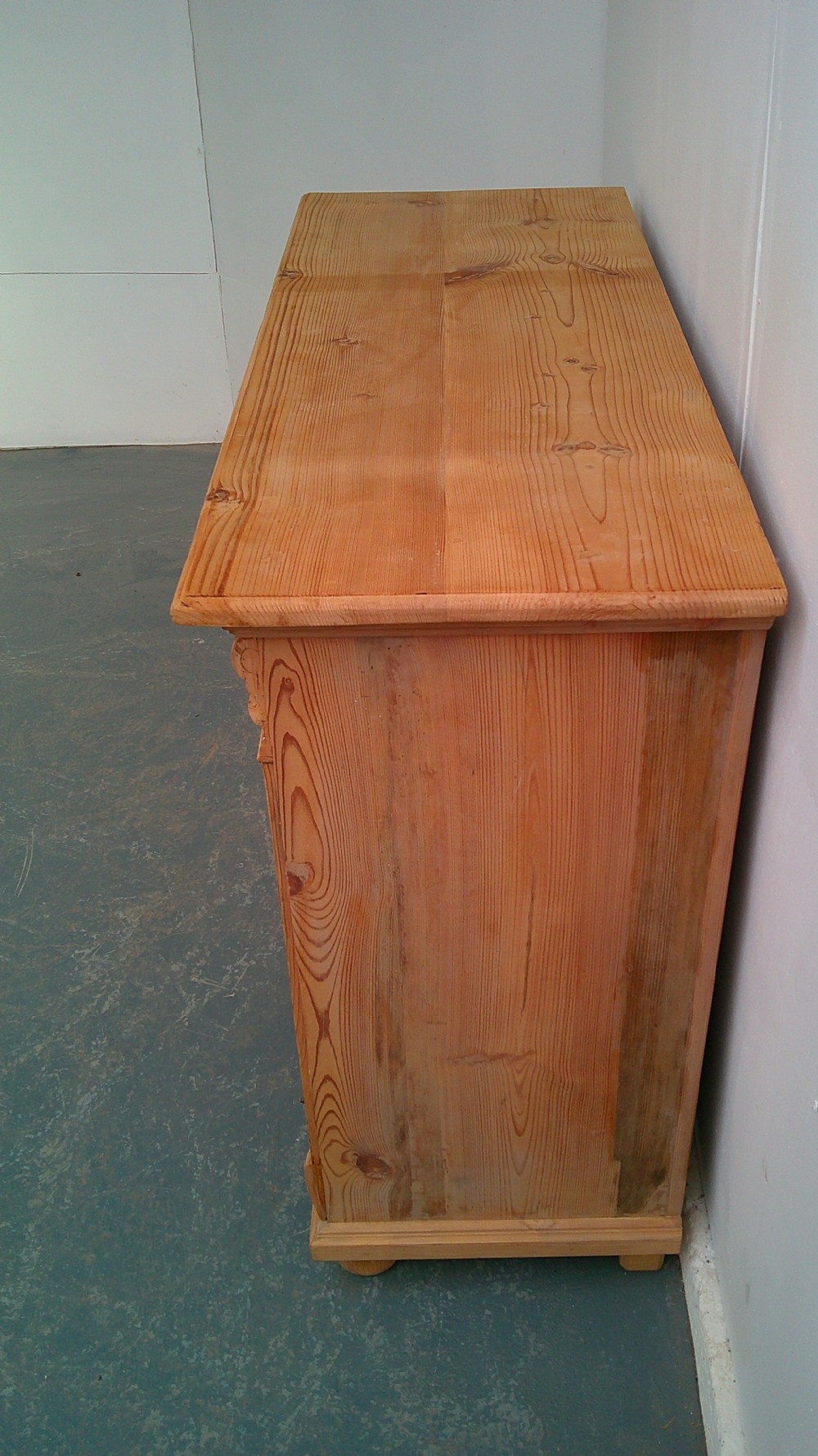 An early Victorian stripped pine shallow dresser base featuring two top drawers over a two-door panelled cupboard with turned bun feet. View III